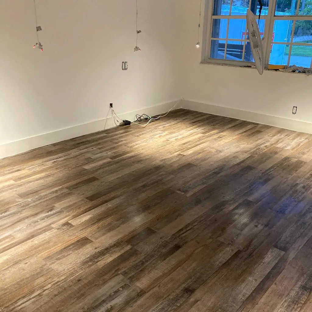 Freshly laid wood plank flooring in an empty residential room part way through a remodel